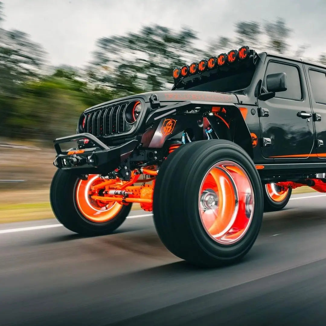 Black Jeep with orange Underglow wheel glow and LED roof lights driving on a road
