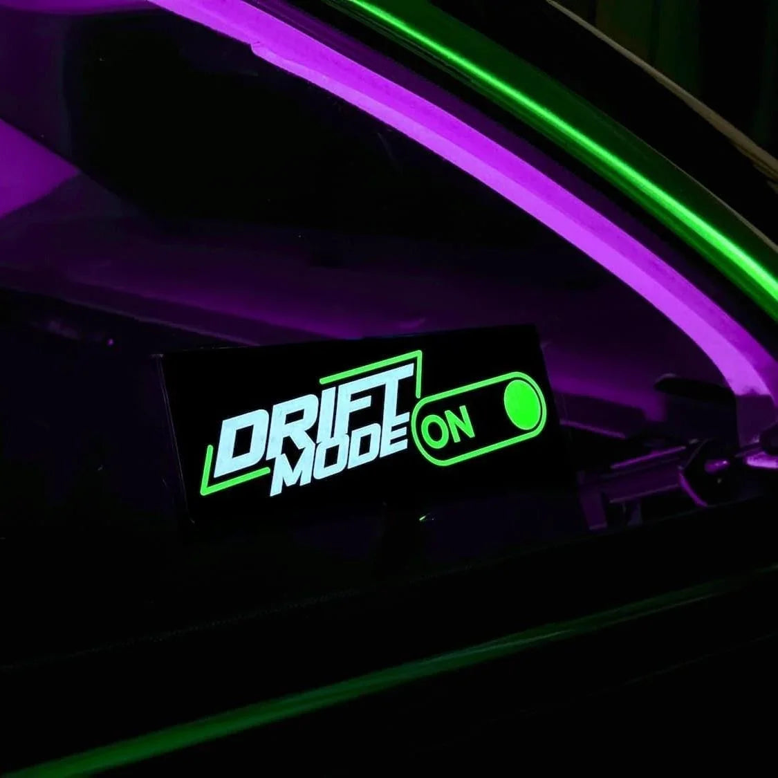Underglow custom green LED decal displaying 'DRIFT MODE ON' inside a car interior.