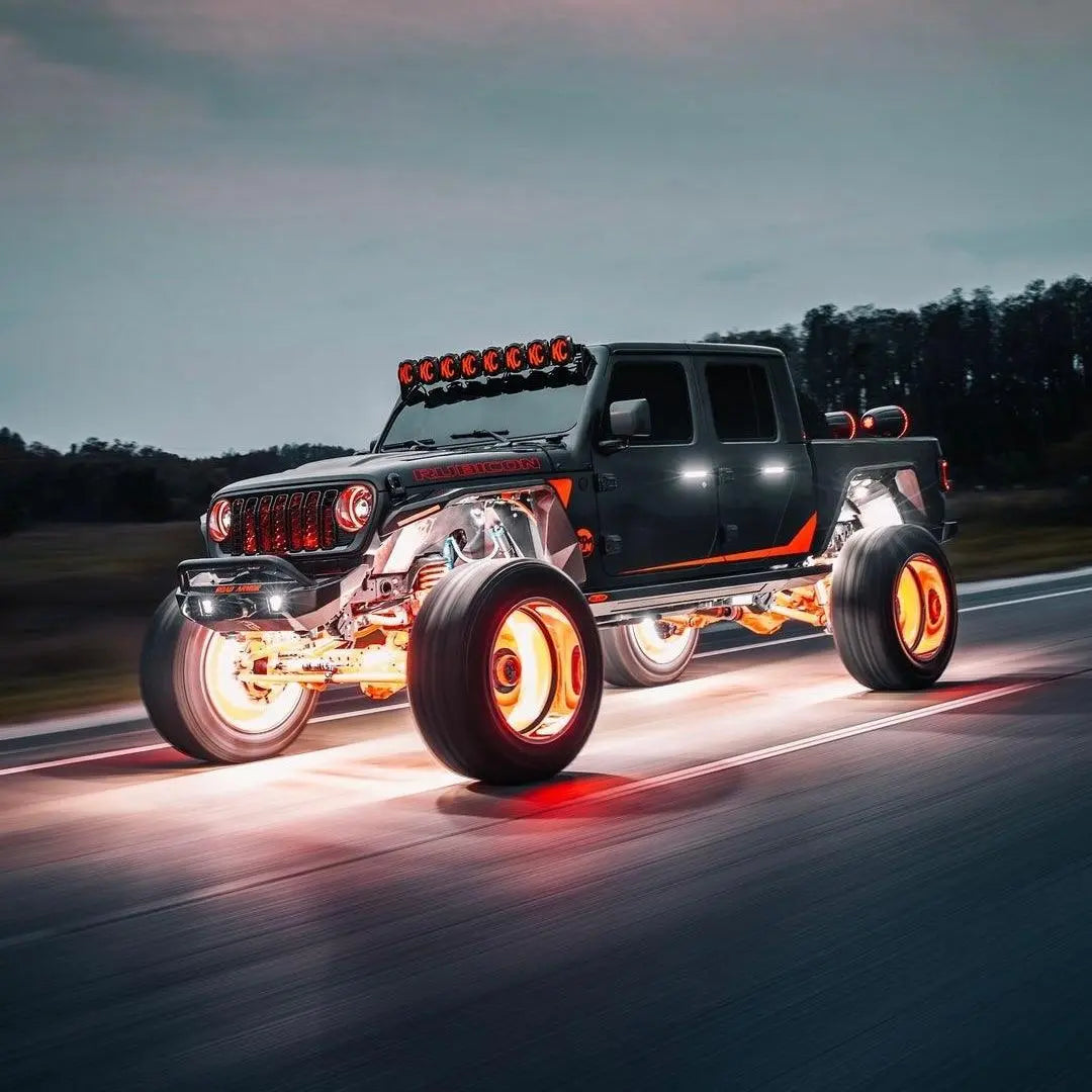 Custom black truck with Underglow orange LED wheel glow and underbody lighting on a road.