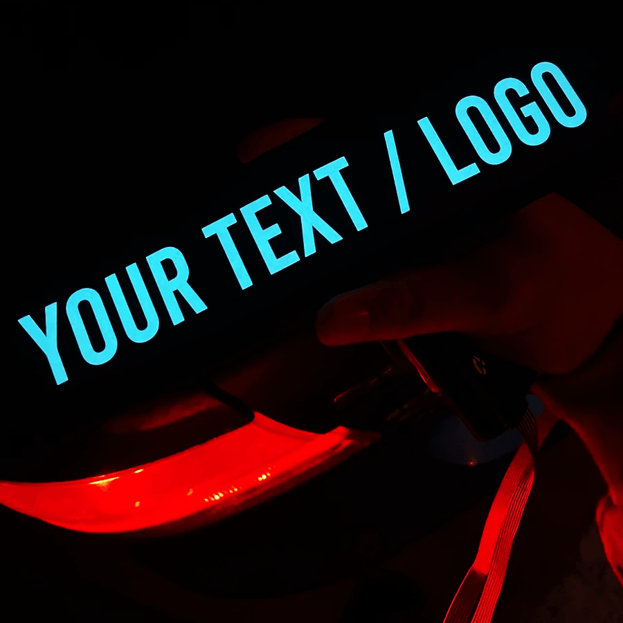 A hand holding a custom blue LED decal displaying 'YOUR TEXT / LOGO' against a dark background.