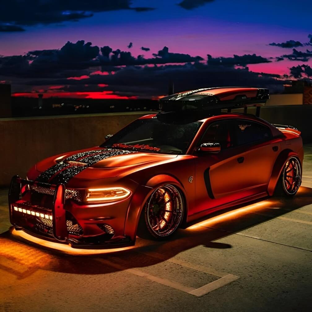 Custom orange muscle car with Underglow LED underglow kits and deep dish wheels at sunset.