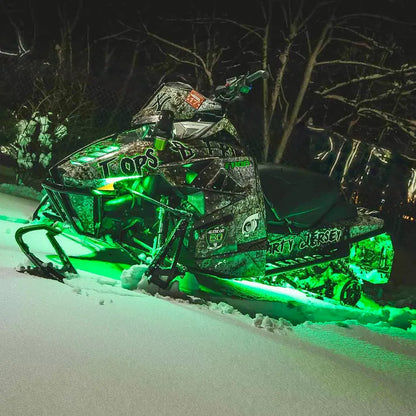 Snowmobile with vibrant green Underglow LED lighting kit in a snowy night setting