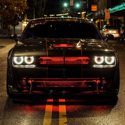 Front view of a black Dodge Challenger with red Underglow engine and grille lighting at night.